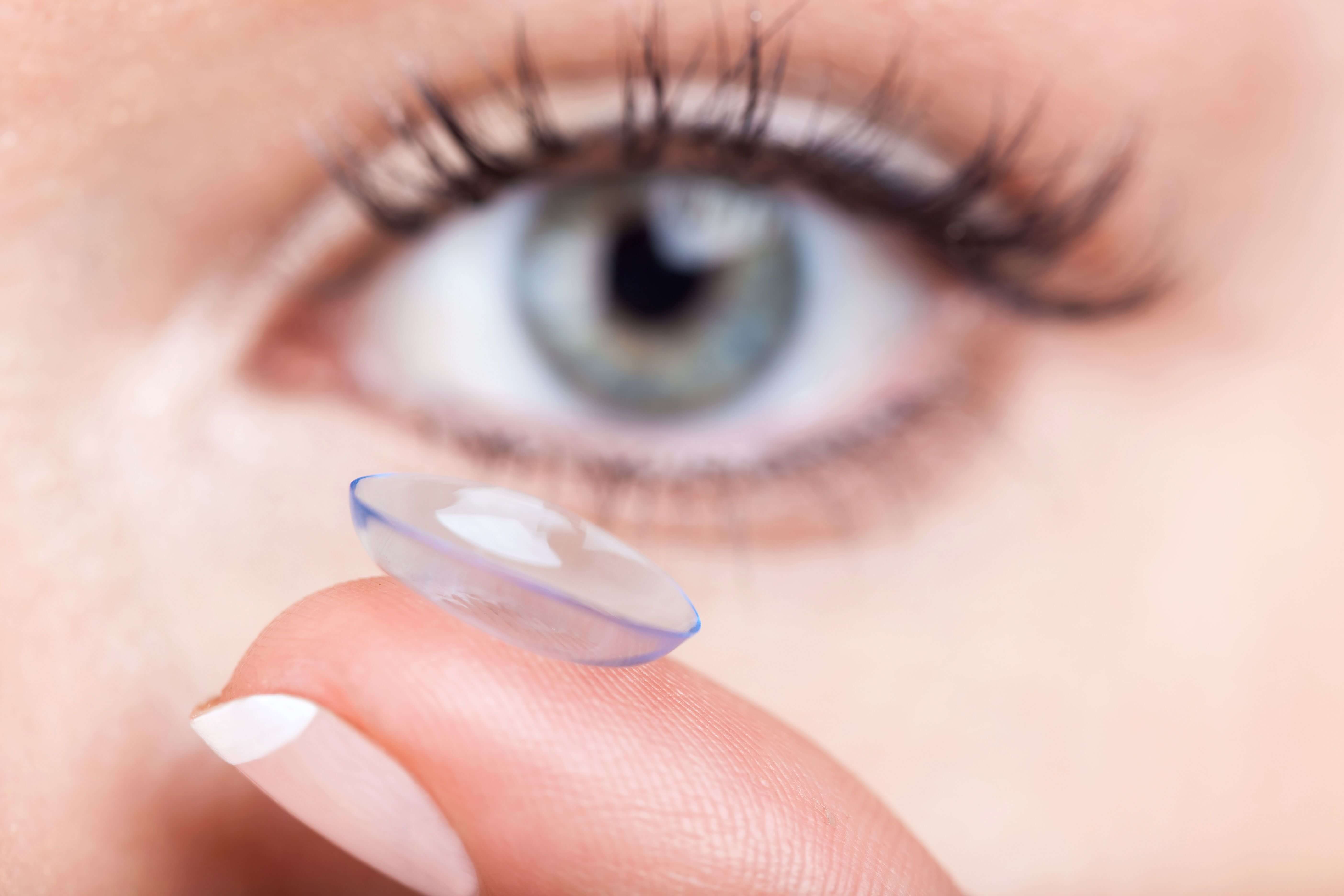 Woman eye with contact lens applying